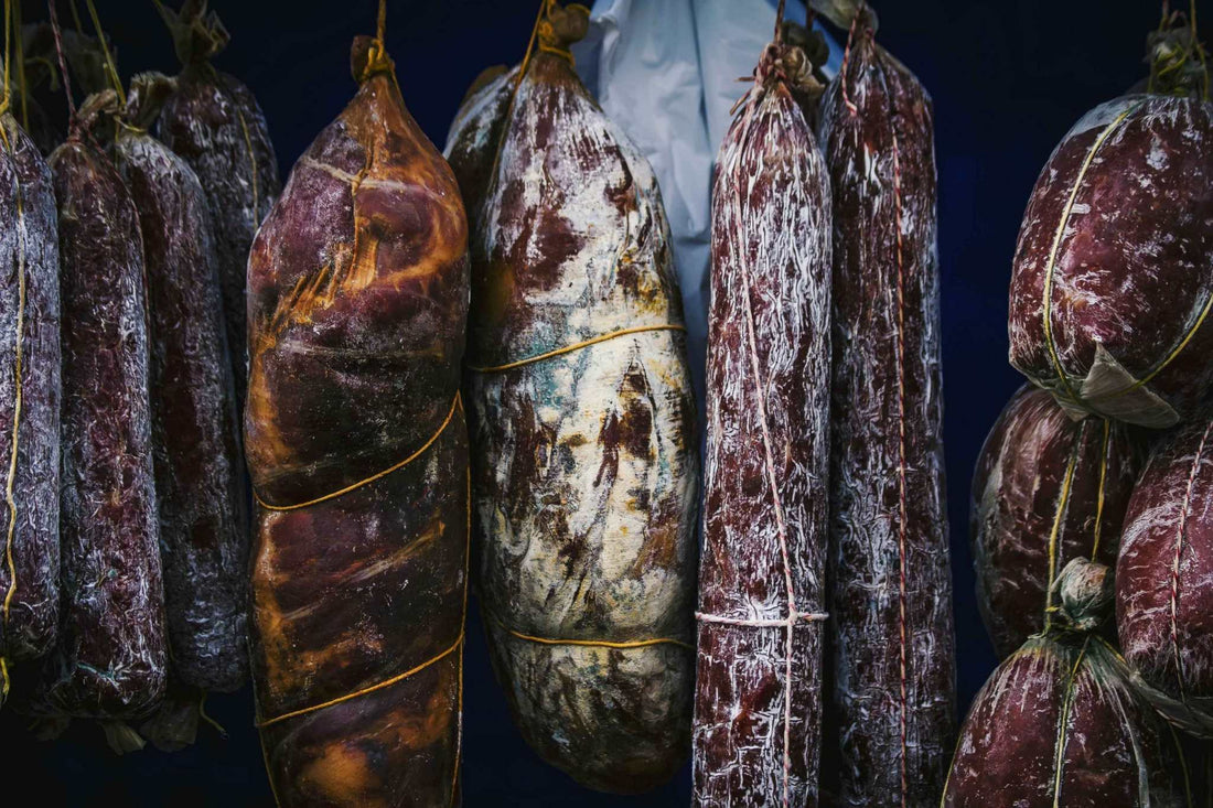 Traditional charcuterie corse sausages and cured meats hanging in a rustic cellar representing authentic Corsican flavors.