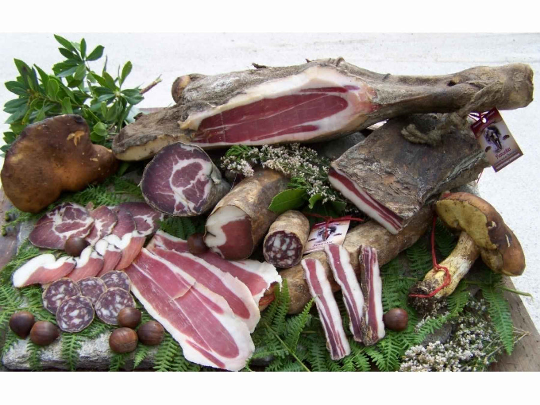 Assorted traditional charcuterie corse including prisuttu, coppa, lonzu, figatellu on rustic natural display with mushrooms and herbs
