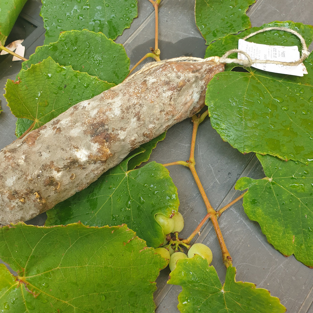 Saucisson fumé de porc IGP sur feuilles de vigne avec étiquette de prix